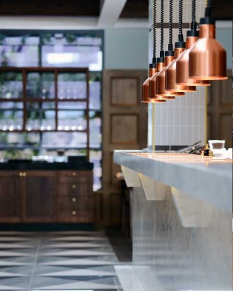 Copper pendant lights over a service area at The Workshop, design by Paul Kelly Design