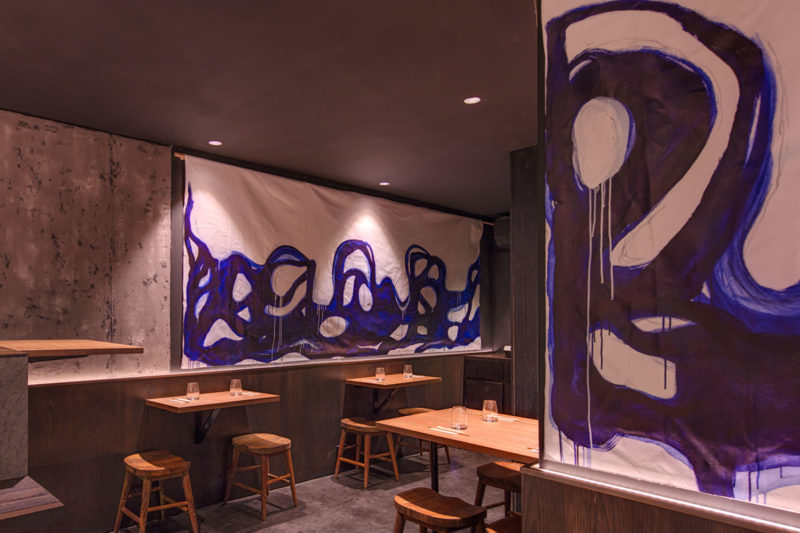 View of the Kenny Rens dining area, timber seats and bold blue brush stroked artwork, interior by Paul Kelly Design